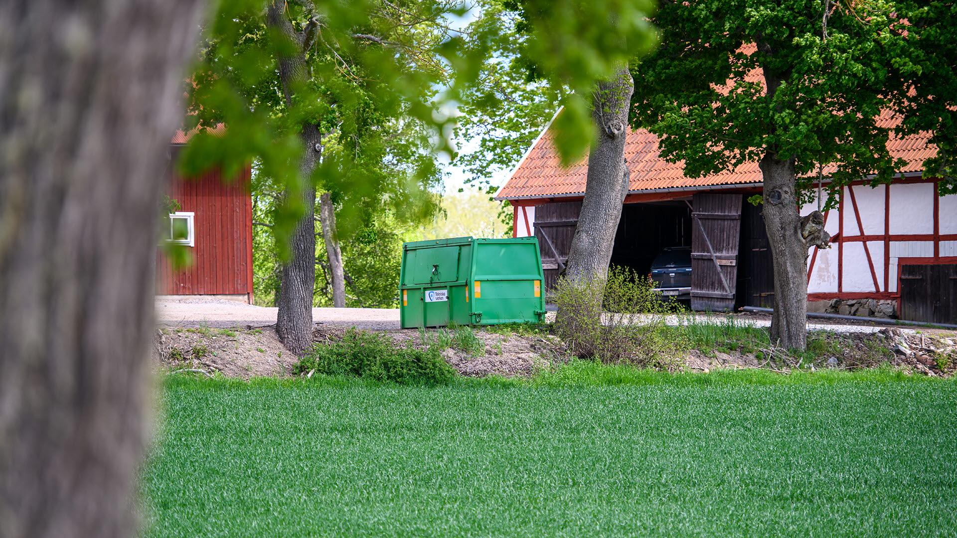 Hyrd grön container står på gårdsplan på landsbygden