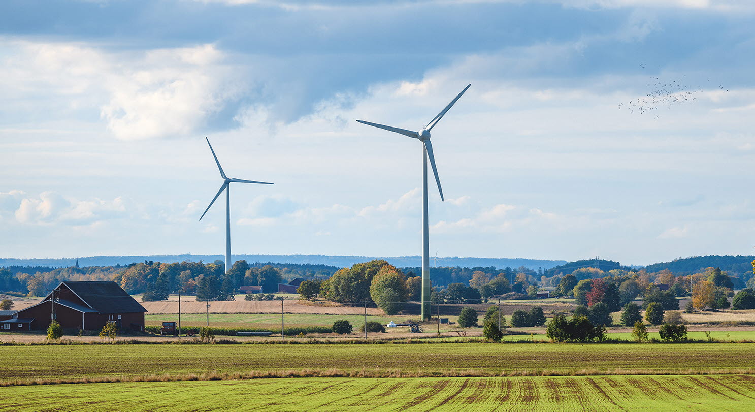 Vindkraftverk mot en blå himmel på slätten i Mjölby