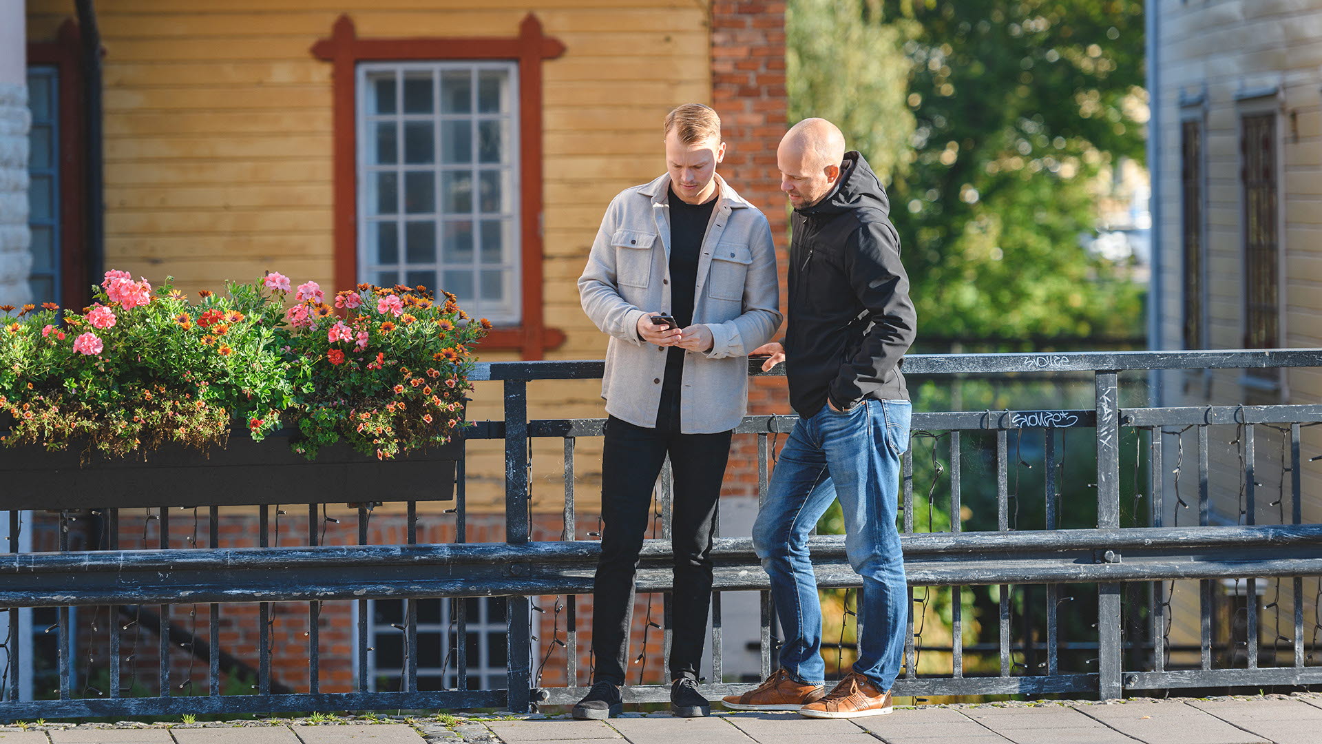 Kunder står på stan i Mjölby och tittar på mobilen